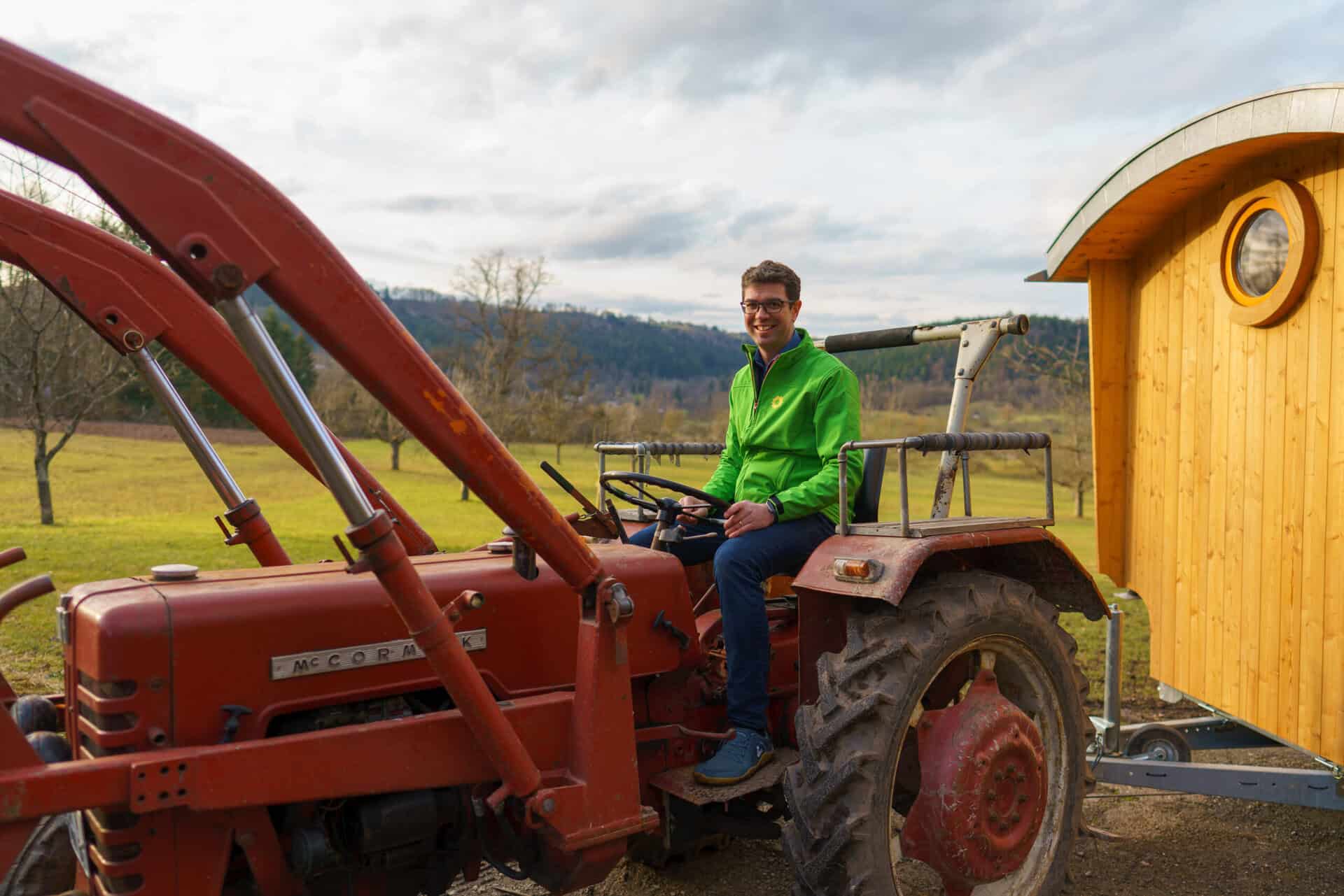 Ralf Nentwich, Mitglied des Landtags Baden-Württemberg, sitzt auf einem alten roten Traktor bei einem Vor-Ort-Besuch im ländlichen Raum